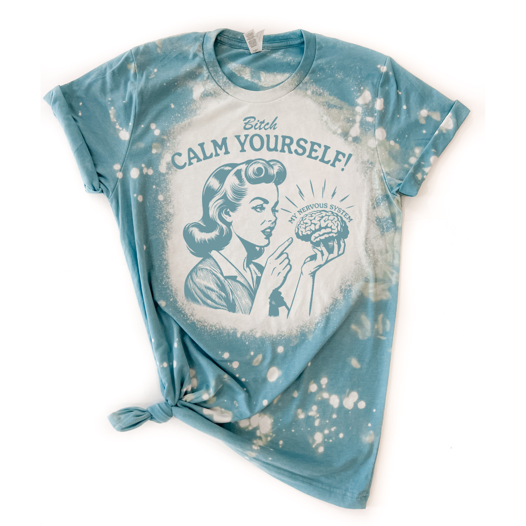 A blue t-shirt with a graphic print that reads 'BITCH CALM YOURSELF!' and features a cartoon illustration of a woman holding a brain The brain says "my nervous system" over the top of it.